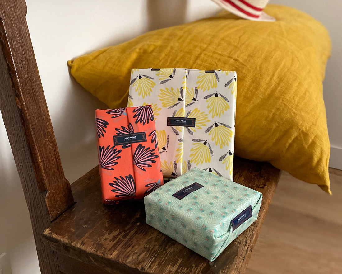 3 petits paquets cadeaux en coton réutilisables sur un banc en bois